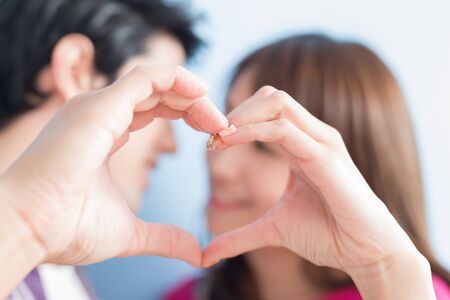 young couple show heart to you isolated on blue backgroundの写真素材