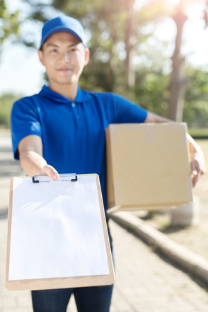 deliveryman take cardboard and smile to you,asianの写真素材