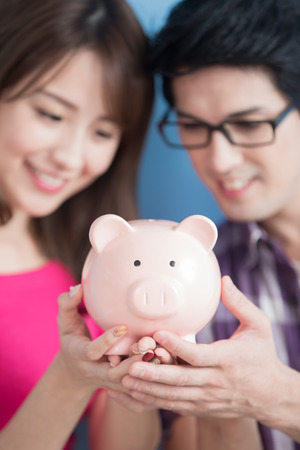 young couple hold pink pig bank and smile happily isolated on blue backgroundの写真素材