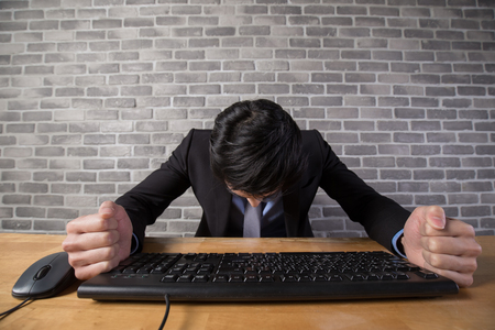 business man feel depressed with brick wall in office,asianの写真素材