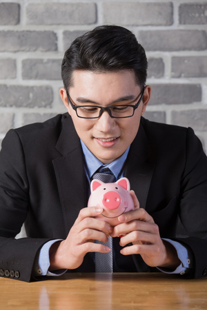 business man take piggy bank in the office, asianの写真素材