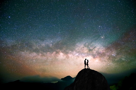 silhouette of couple with night scene milky way background in the galaxyの写真素材