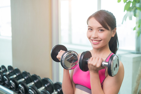 sport woman hold dumbbell and training hard in the gymの写真素材