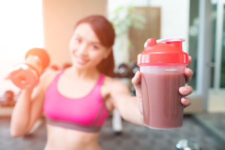 sport woman hold dumbbell and protein in the gymの写真素材