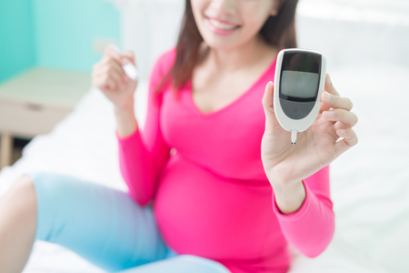 beauty pregnancy woman with glucometer on the bedの写真素材