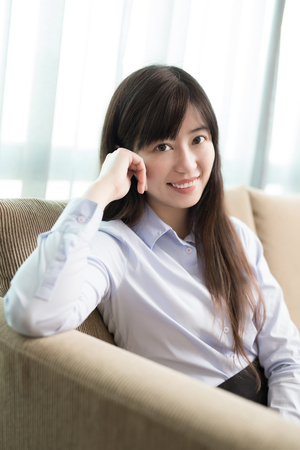 business woman smile happily and sit on sofa in officeの写真素材