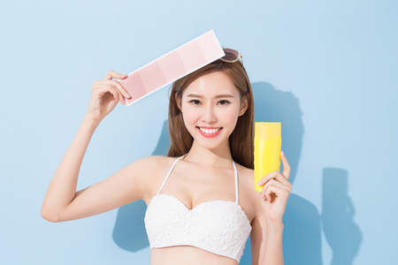woman take skin color scale and sunscreen on the blue backgroundの写真素材