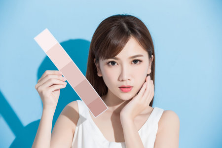 woman take skin color scale on the blue backgroundの写真素材