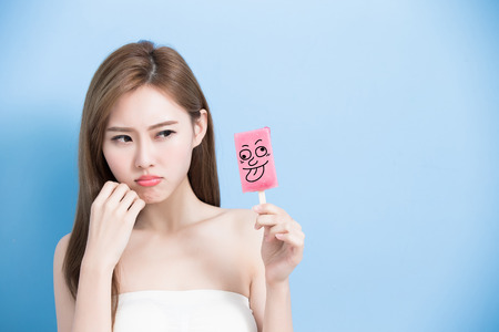 woman take popsicle and feel upset with sensitive problem on the blue bakcgroundの写真素材