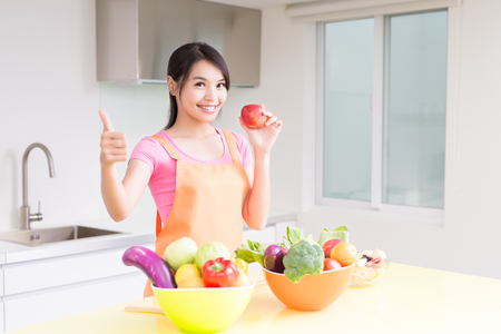 beauty housewif take apple and thumb up in the kitchenの写真素材