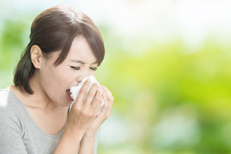 woman get sick and blow her nose on the green backgroundの写真素材