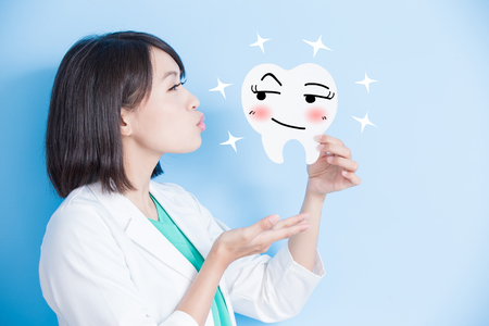 woman dentist kiss and take tooth board on the blue backgroundの写真素材