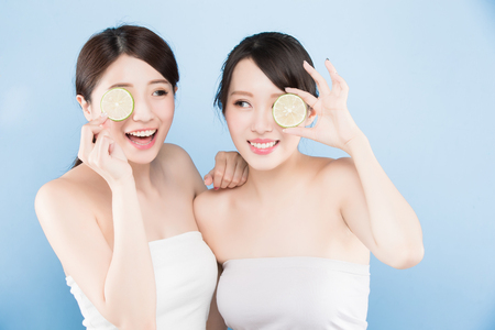 two beauty woman take lemon with make up concept on the blue backgroundの写真素材