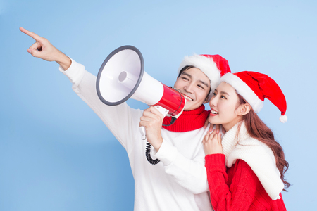 couple take microphone and show something with merry christmas on the blue backgroundの写真素材