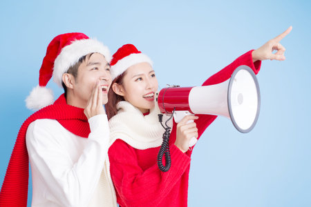 Couple take microphone and show something with merry Christmas on the blue backgroundの写真素材