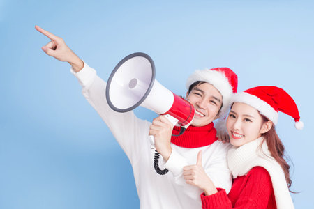 Couple take microphone and show something with merry Christmas on the blue backgroundの写真素材