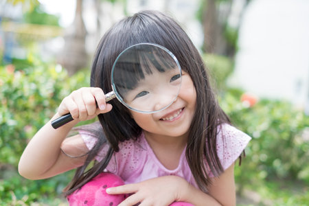 cute girl take magnifying in the parkの写真素材
