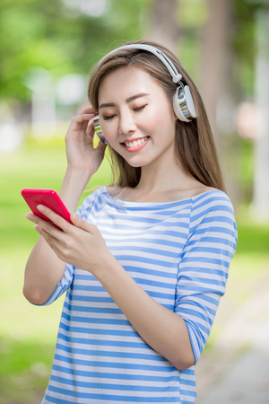 woman smile happily and use phone listen music in the parkの写真素材