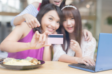 close up of woman friends take credit card and laptop in restaurantの写真素材