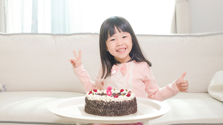 cute girl with birthday cake in the homeの写真素材