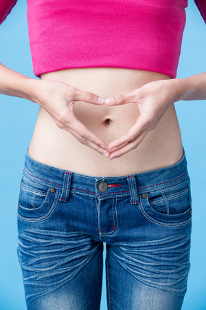 woman show heart gesture with belly on the blue backgroundの写真素材