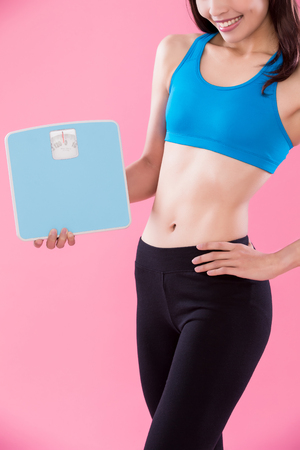 sport woman take weight scale on the pink backgroundの写真素材