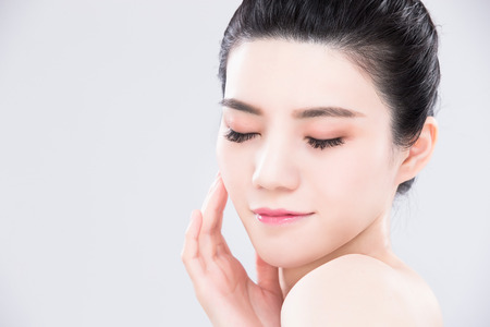woman close eyes and touch face with beauty skin care concept on the gray backgroundの写真素材