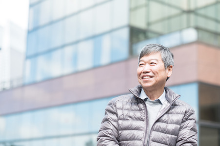 old man smile happily and look somewhere with business buildingの写真素材