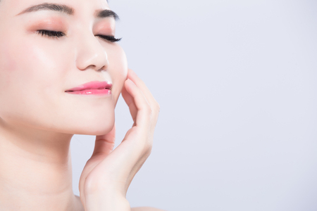 woman close eyes and touch face with beauty skin care concept on the gray backgroundの写真素材