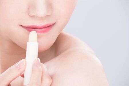 woman use lip balm on the gray backgroundの写真素材