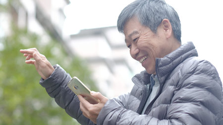 old man use phone happily in the park