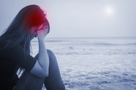 woman sit and feel headache in the seasideの写真素材