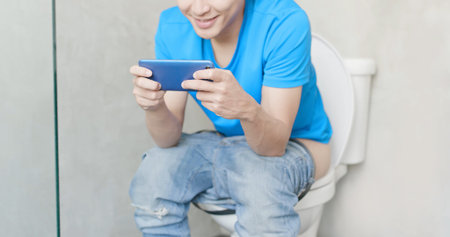 man take phone and smile happily in the toilet