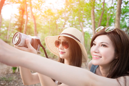 two beauty woman take camera look somewhere and go travel happily in the forest