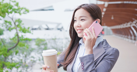 businesswoman take coffee and speak on phone happilyの写真素材