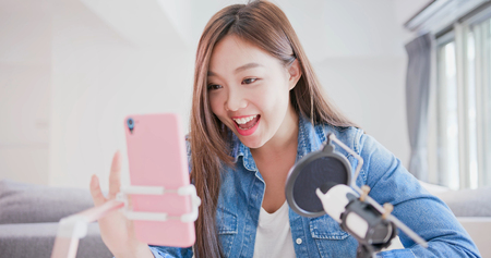 woman having live stream on cellphone at homeの写真素材