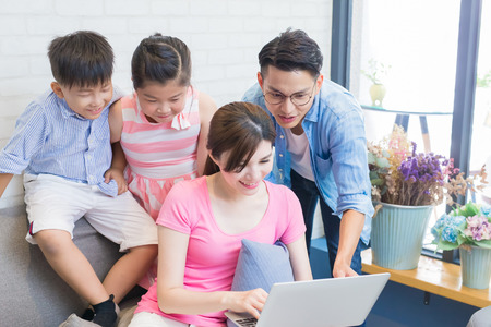 happily family sit on sofa and use notebook at home