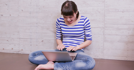 woman use notebook happily and sit on the floor at homeの写真素材