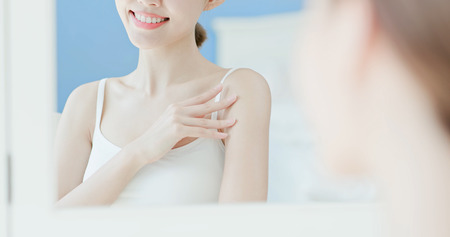 beauty woman look mirror and apply cream with arm at homeの写真素材