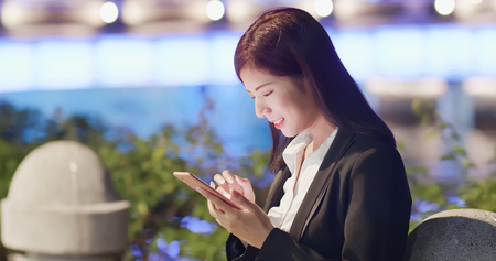woman use phone in city at nightの写真素材
