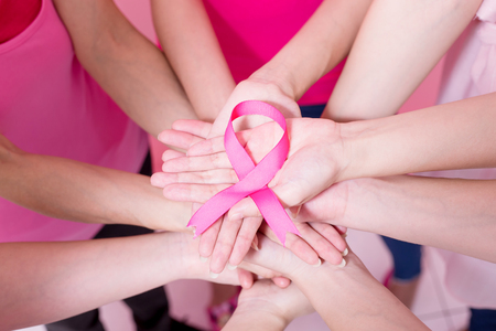 women show pink ribbon with breast cancer prevention on the pink backgroundの写真素材