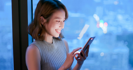 woman use phone happily in building at nightの写真素材