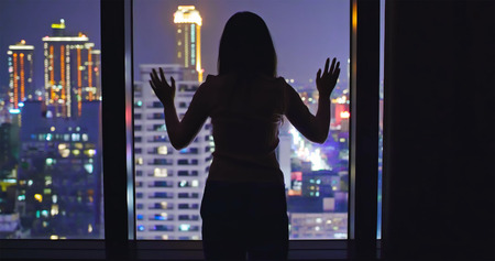woman look outside in the building at nightの写真素材