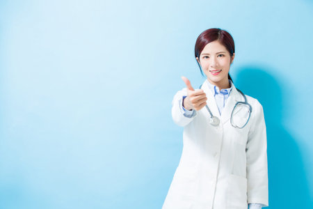 woman doctor thumb up on the blue backgroundの写真素材