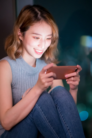 woman play mobile game happily indoor at nightの写真素材
