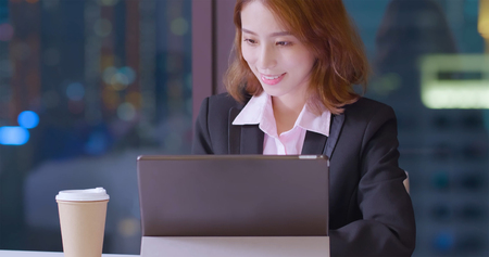 business woman smile happily and use digital tablet work at nightの写真素材