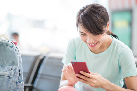 woman sit and use phone happily in the stationの写真素材