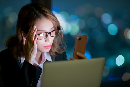 business woman use phone and notebook work at nightの写真素材