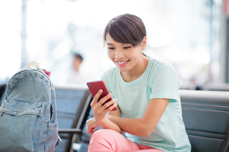 woman sit and use phone happily in the stationの写真素材