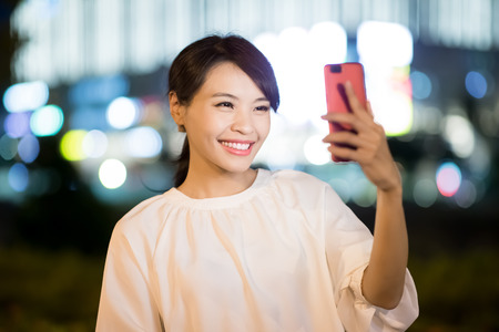 woman use smart phone selfie happily at nightの写真素材